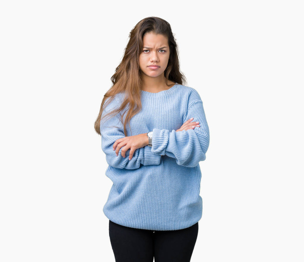 Mujer morena hermosa joven con suéter azul de invierno sobre fondo aislado escéptico y nervioso, desaprobando la expresión en la cara con los brazos cruzados. Persona negativa
. - Foto, Imagen