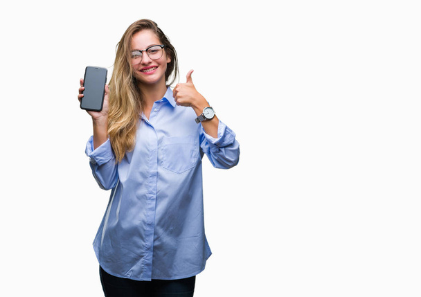 Giovane bella donna d'affari bionda che mostra lo schermo dello smartphone su sfondo isolato felice con grande sorriso facendo segno ok, pollice in su con le dita, segno eccellente
 - Foto, immagini
