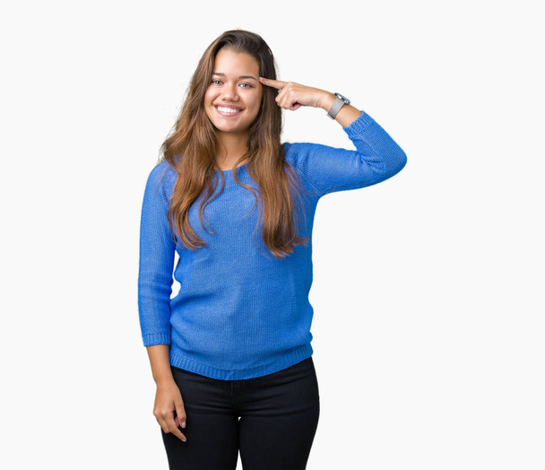 Jonge mooie brunette vrouw blauwe trui te dragen over geïsoleerd background Smiling wijzend naar hoofd met één vinger, geweldig idee of gedachte, goed geheugen - Foto, afbeelding