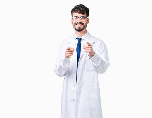 Молодий професійний вчений чоловік носить біле пальто над ізольованим тлом, вказуючи пальці на камеру з щасливим і смішним обличчям. Хороша енергія і вібрує
. - Фото, зображення