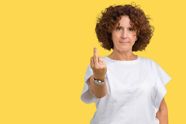 Красива старша жінка середнього віку в білій футболці над ізольованим тлом Показує середній палець, неввічливий і грубий хуй вираз
 - Фото, зображення