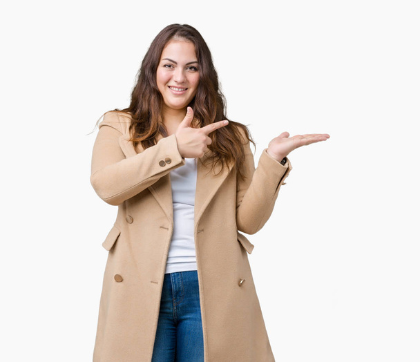 プラスサイズの若い女性は美しい背景驚くし、手とを提示、指で指している間カメラに笑顔を分離で冬のコートを着て. - 写真・画像