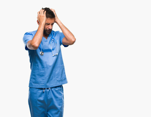 Erwachsene hispanische Arzt oder Chirurg Mann mit isoliertem Hintergrund leiden unter Kopfschmerzen verzweifelt und gestresst, weil Schmerzen und Migräne. Hände auf den Kopf. - Foto, Bild