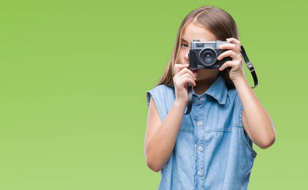 Fiatal szép lány, fényképek segítségével vintage kamera elszigetelt háttér, a gondolkodás súlyos Szúró Szembenéz magabiztos kifejezés - Fotó, kép