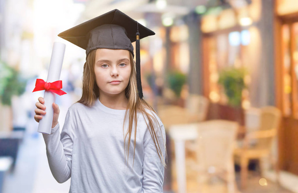 Young beautiful girl wearing graduate cap holding degree over isolated background with a confident expression on smart face thinking serious - Photo, Image