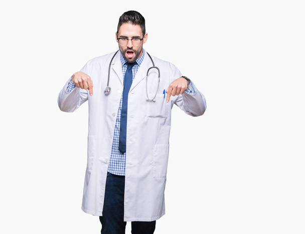 Красивый молодой врач на изолированном фоне, указывая пальцами на рекламу, удивленное лицо и открытый рот
 - Фото, изображение