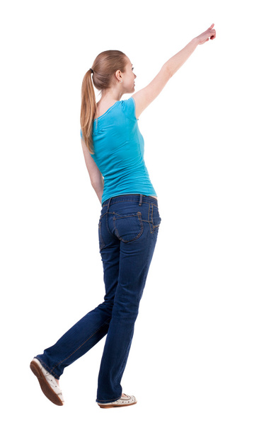 back view of walking woman in jeans and shirt pointing - Foto, Imagen