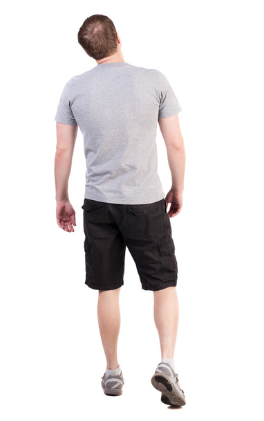 Back view of walking handsome man in shorts and sneakers - Foto, Bild