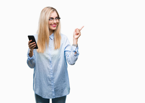 Jeune belle femme d'affaires blonde utilisant smartphone sur fond isolé très heureux pointant avec la main et le doigt sur le côté
 - Photo, image