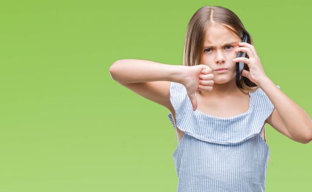 Krásná mladá dívka mluví po telefonu izolované pozadí s naštvaný obličej, záporné znaménko ukazující nechuť s palci dolů, koncept odmítnutí - Fotografie, Obrázek