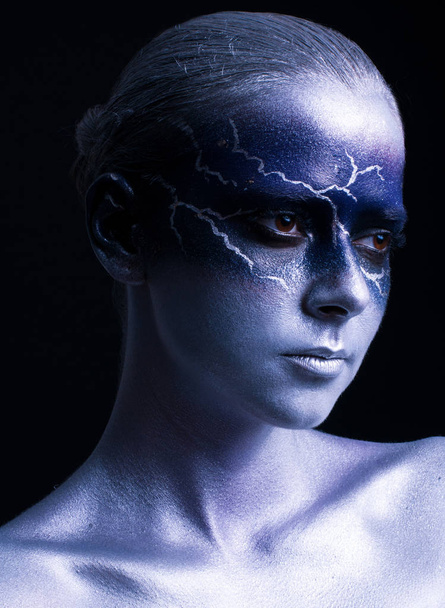 Portrait of young beautiful woman with lightning design face art on black background. Female lightning design body art. Blue silver face art. - Photo, Image