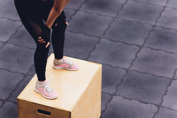 Athletic woman stands on a wooden box in a gym club. - Foto, Imagem