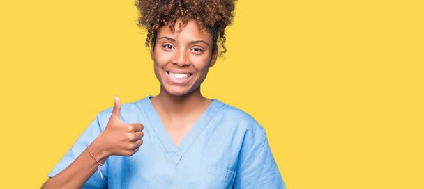 Молодий афроамериканець лікар жінка над ізольованих фон робити щасливим великі пальці вгору жестом рукою. Затвердження вираз, дивлячись на камеру з зазначенням успіху. - Фото, зображення