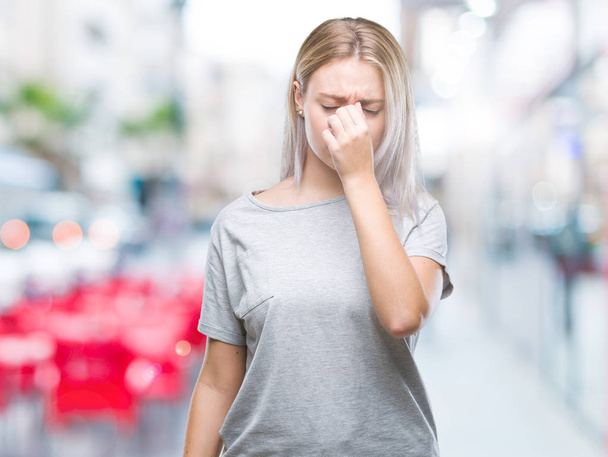Young blonde woman over isolated background tired rubbing nose and eyes feeling fatigue and headache. Stress and frustration concept. - Foto, Imagen