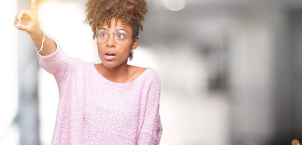 Güzel genç Afro-Amerikan kadın üzerinde gözlük takan izole arka plan ile sürpriz devam parmakla, açık ağız hayret ifadesi, önünde bir şey - Fotoğraf, Görsel