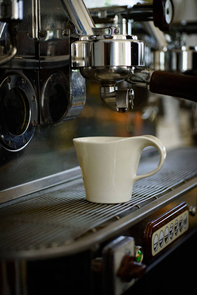 Para una taza de café espresso perfectamente elaborada. Pequeña taza para servir café o bebidas expreso. Café. Cafetera de acero inoxidable o cafetera. Preparación de café en cafetería comercial o cafetería
 - Foto, Imagen