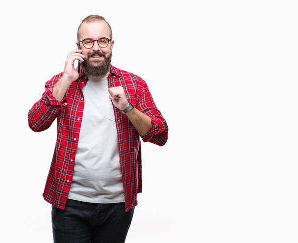Young caucasian hipster man talking on smartphone over isolated background with surprise face pointing finger to himself - Photo, Image