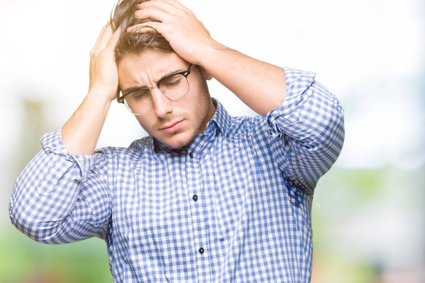 Homem bonito jovem usando óculos sobre fundo isolado sofrendo de dor de cabeça desesperada e estressada porque dor e enxaqueca. Mãos na cabeça
. - Foto, Imagem