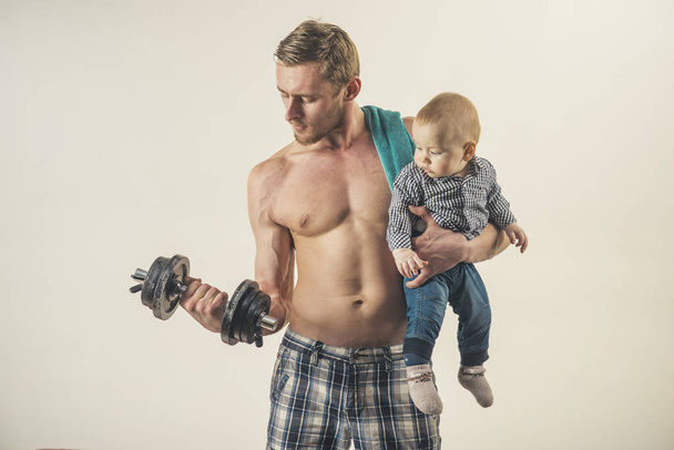 Time to sport. Father build biceps triceps with son. Healthy family lifestyle. Strong man with dumbbells hold baby boy. Father and child training together. Active family enjoy sport and fitness - 写真・画像