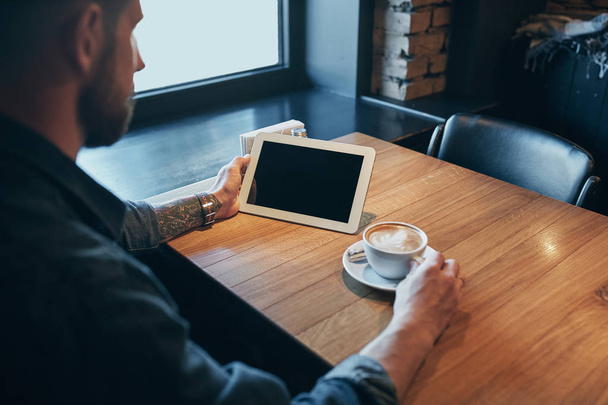 Κλείστε επάνω τα χέρια άνθρωπος χρησιμοποιώντας tablet, τη σύνδεση Wi-Fi. Εργάζονται ακριβώς από το café. Μαύρη οθόνη - Φωτογραφία, εικόνα