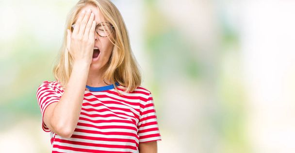 Beautiful young woman wearing glasses over isolated background Yawning tired covering half face, eye and mouth with hand. Face hurts in pain. - Photo, Image