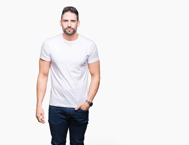 Young man wearing casual white t-shirt over isolated background Relaxed with serious expression on face. Simple and natural looking at the camera. - Valokuva, kuva