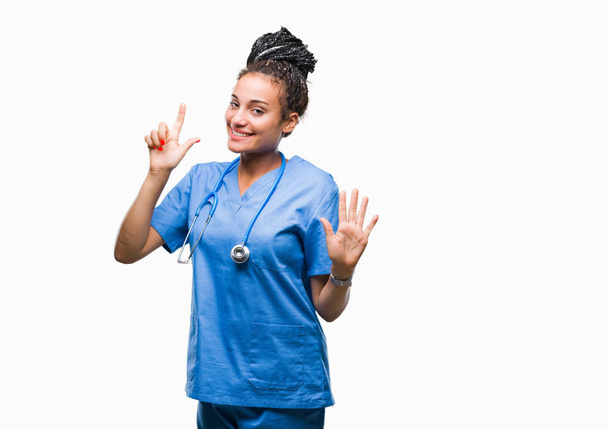 Young braided hair african american girl professional surgeon over isolated background showing and pointing up with fingers number seven while smiling confident and happy. - Foto, immagini