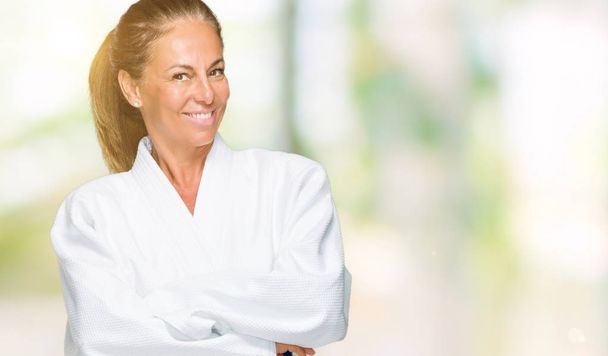 Взрослая женщина средних лет в форме карате-кимоно на изолированном фоне счастливое лицо, улыбающееся со скрещенными руками, смотрящее в камеру. Позитивный человек
. - Фото, изображение