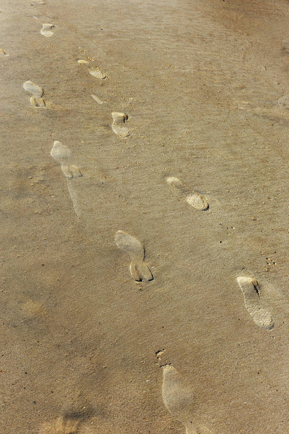 Impronte umane insolite sulla spiaggia di sabbia. Un certo numero di impronte umane in direzioni diverse con un piede solo. effetto insolito sulla sabbia marina. Colpo verticale con spazio di copia
 - Foto, immagini