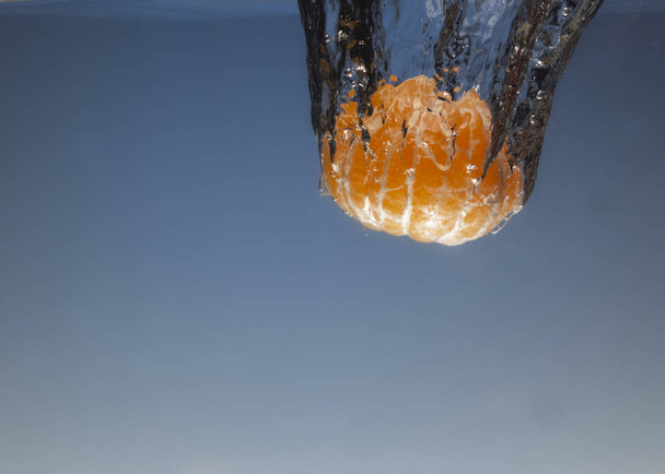 mandarina sin cáscara lanzada al agua. Vista desde debajo del agua de cerca
 - Foto, Imagen
