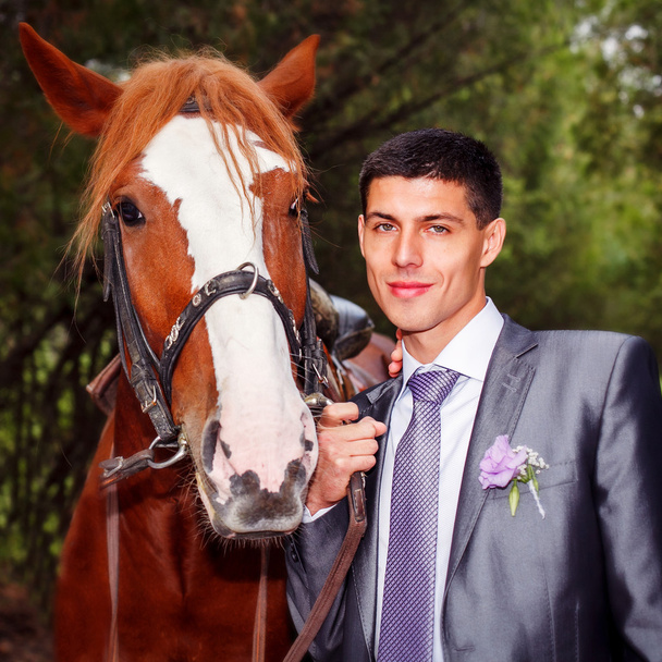 Portrait of the groom with a horse - Photo, Image
