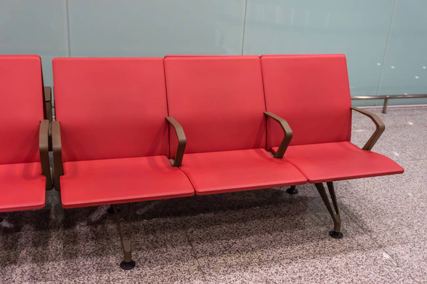 Fila de asientos del aeropuerto de color rojo en la sala de reclamos de equipaje
 - Foto, Imagen