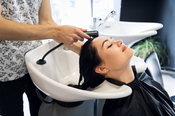 Перукарня. Жінка сидить під час миття волосся в салоні
. - Фото, зображення