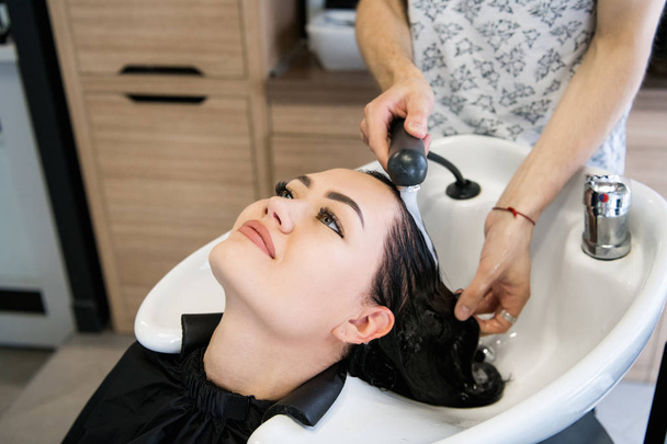 Kadeřnický salon. Krásná bruneta žena při mytí vlasů - Fotografie, Obrázek
