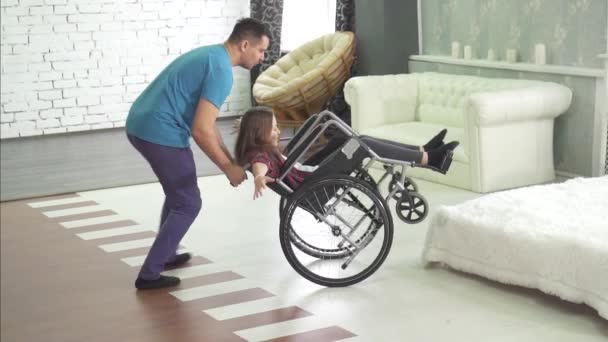 joyful disabled child in a wheelchair at home with his father - Imágenes, Vídeo
