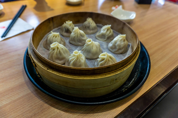 Diez Dumplings Xiaolongbao al vapor chinos en un vapor de bambú
 - Foto, Imagen