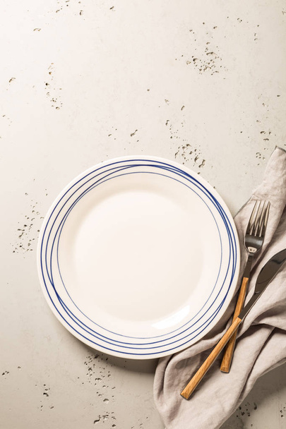 Empty white plate, napkin and cutlery on grey stone background. Composition captured from above (top view, flat lay), layout with free text (copy) space. - Fotó, kép
