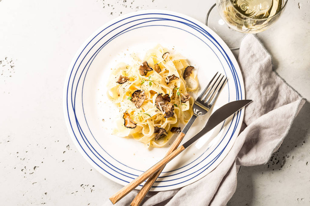 Tagliatelle pasta with black truffles and parmesan cheese. Plate captured from above (top view, flat lay). Grey stone background. Layout with free text space. - 写真・画像