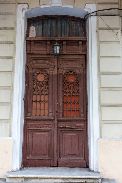 Старая деревянная дверь. Пережившие трещины краски настолько старые деревянные двери в стене древнего каменного дома в исторической части Одессы, Украина. Старая каменная стена с цементной входной дверью
 - Фото, изображение