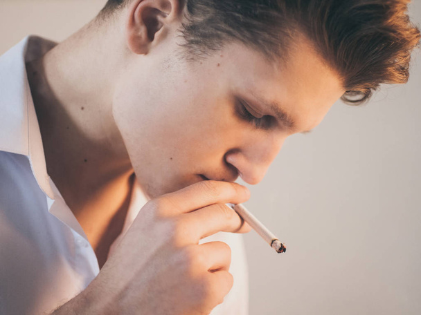 Young handsome guy man smoking a cigarette, studio shooting. - Foto, afbeelding