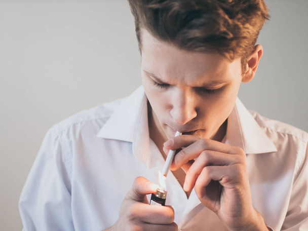 Young handsome guy man smoking a cigarette, studio shooting. - Fotó, kép