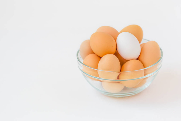 Many brown eggs with one white egg in a glass bowl. While cooking in the kitchen ingredients. - Fotografie, Obrázek