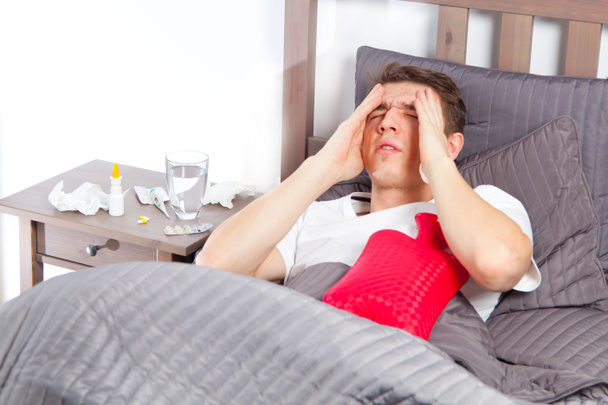 Homem sentindo-se mal deitado na cama e tosse
 - Foto, Imagem