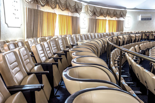 Lichte interieur van een moderne concertzaal met een etappe en rijen van comfortabele lederen stoelen, een etappe en het systeem van de akoestische versterking onder natuurlijke licht, bereid voor presentatie - Foto, afbeelding