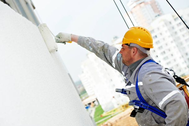 builder worker painting facade of building with roller - Fotó, kép