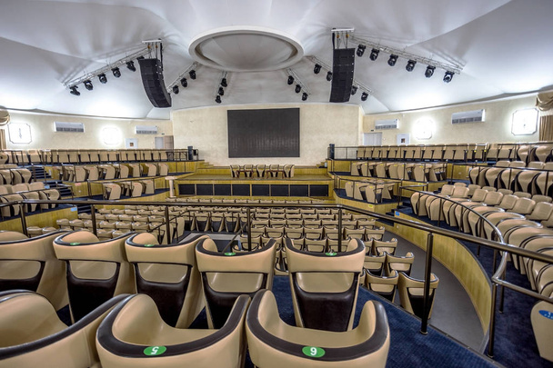 helles Interieur eines modernen Konzertsaals mit Bühne und bequemen Ledersesselreihen, Bühne und akustischem Verstärkungssystem unter Tageslicht, für die Präsentation vorbereitet - Foto, Bild