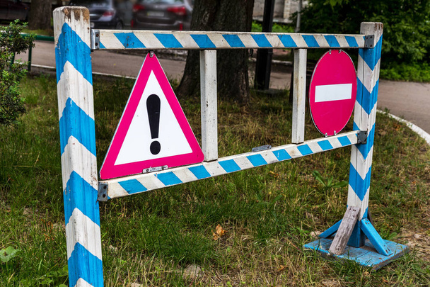 Holzgeländer, Zaun und das Verkehrszeichen, das vor und während der Fahrt warnt, sind verboten. Straße gesperrt. Verbotsschilder blockieren den Straßenverkehr - Foto, Bild