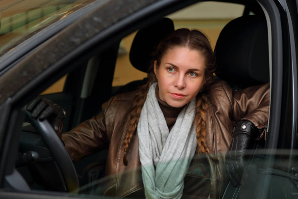 Beautiful stylish girl in a leather jacket and gloves driving a car - Foto, immagini