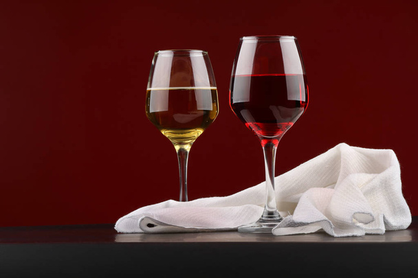 Still life with glasses of red and white wine on Burgundy background - Foto, Imagen