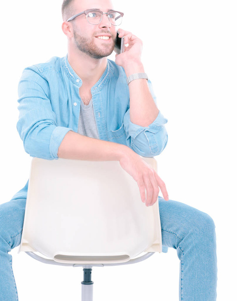 Young man sitting on chair and using mobile phone. Startupper. Young entrepreneur. - Фото, изображение
